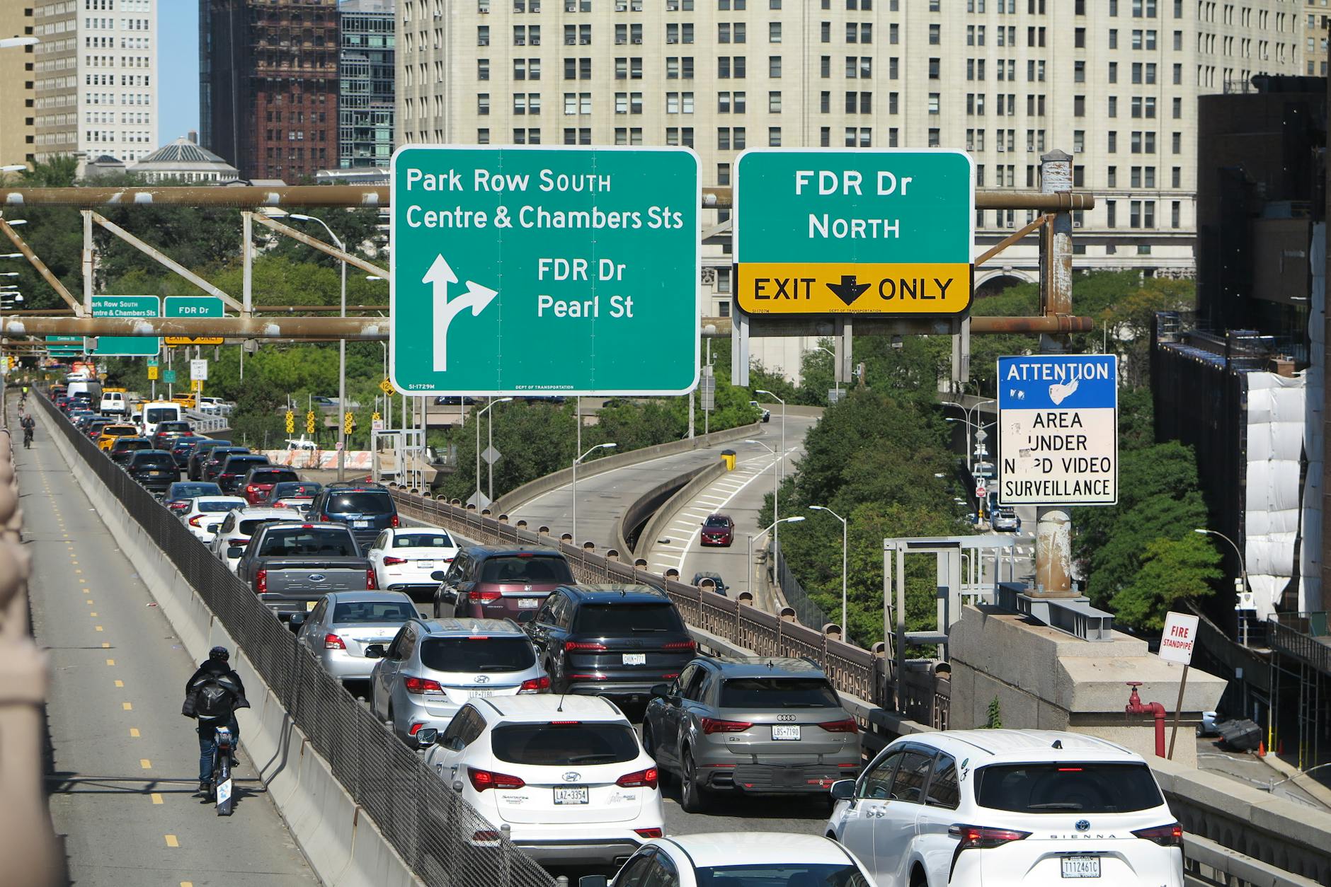 Gęsty ruch na wielopasmowej drodze z tablicami kierującymi na Brooklyn Bridge