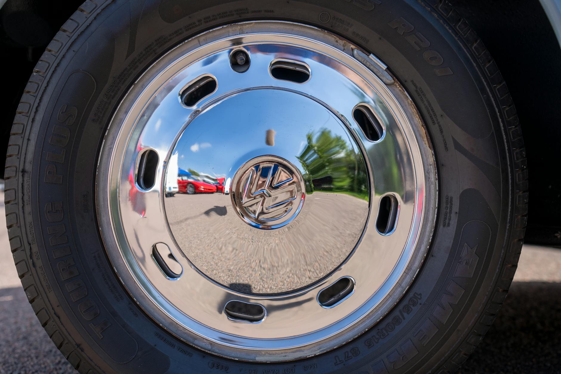 Chromowane koło samochodu osobowego odbijające krajobraz przy drodze