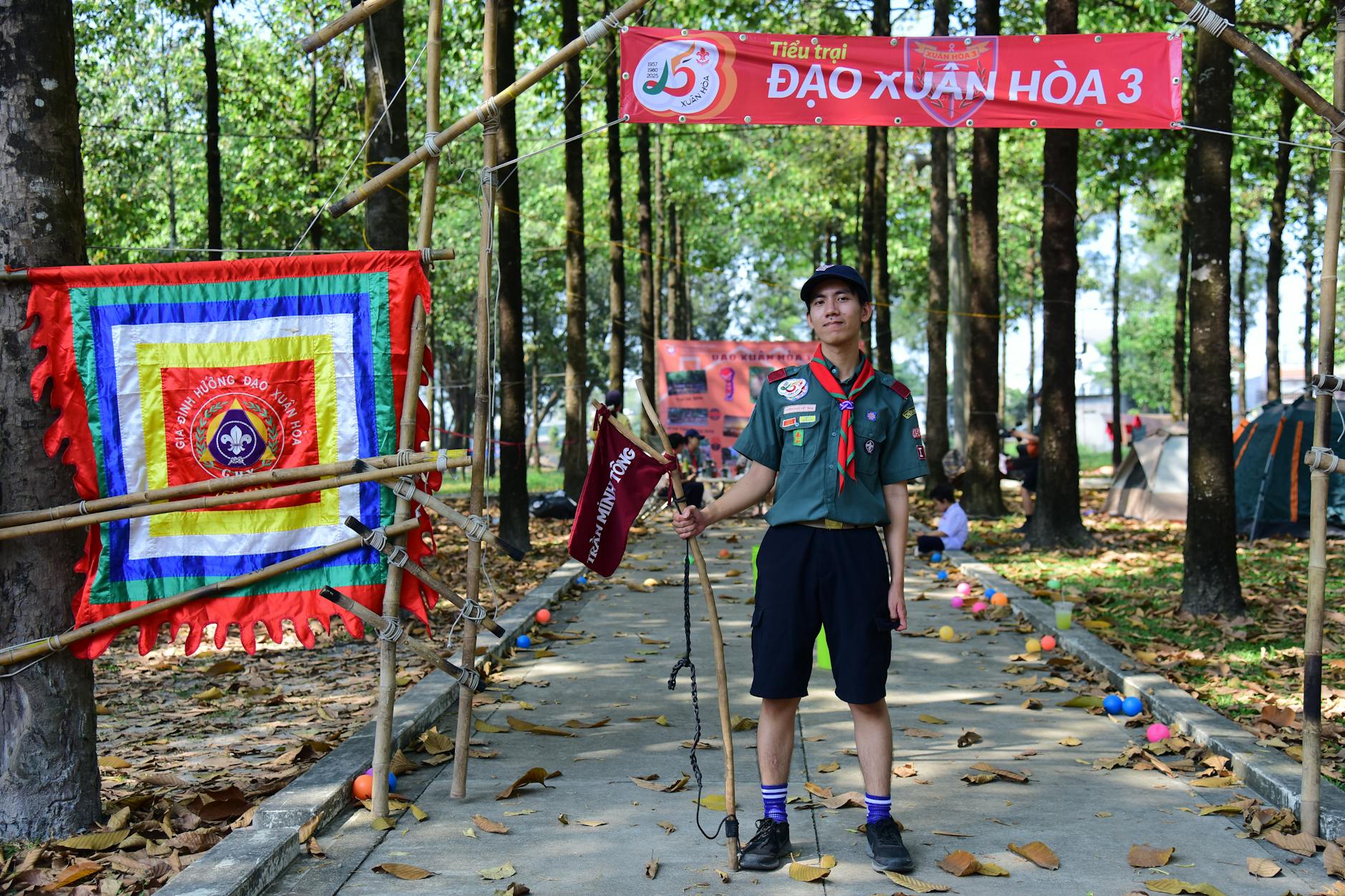 Harcerski obóz pod gołym niebem z instruktorem i kolorowymi flagami