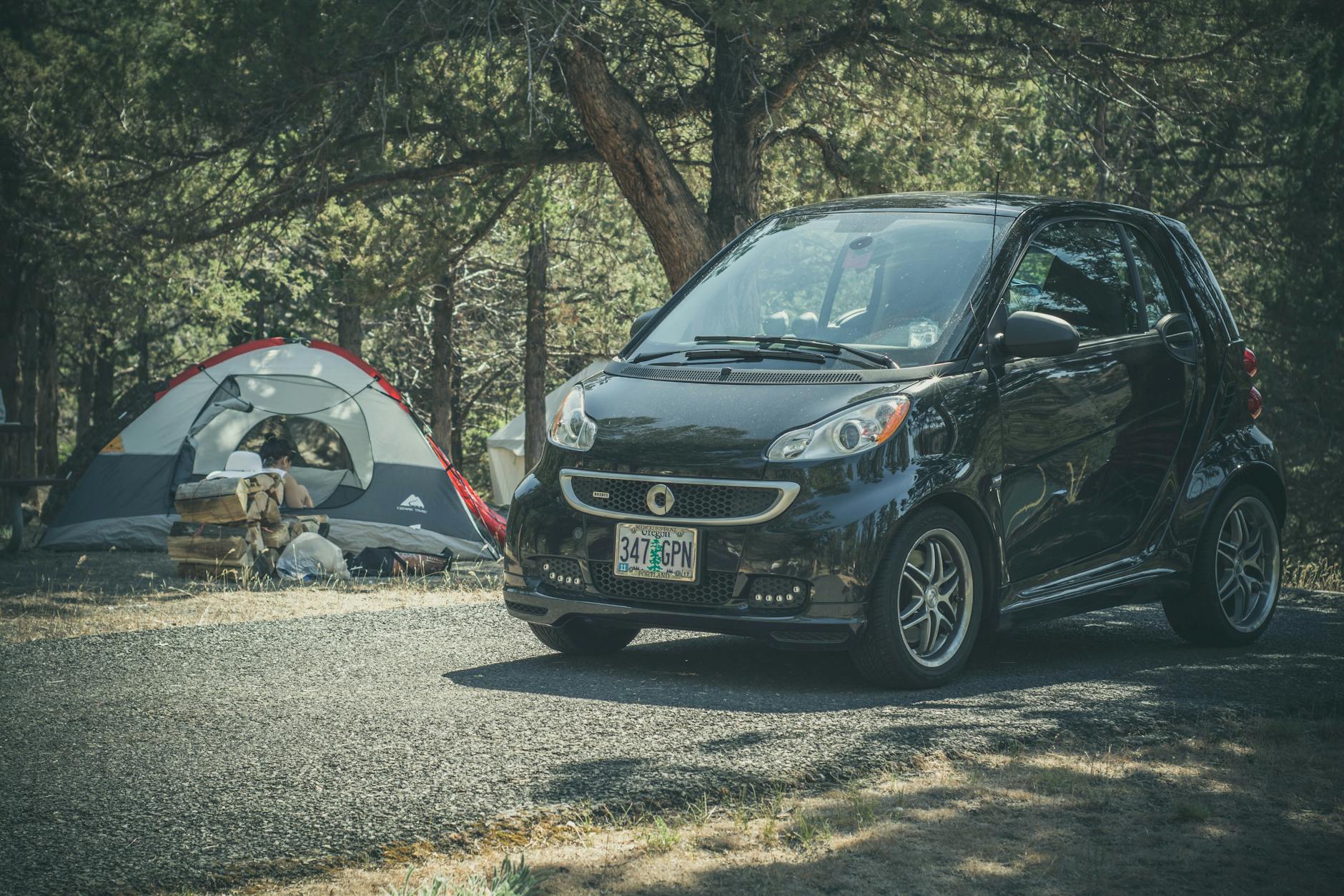 Samochód zaparkowany przy namiocie na leśnym kempingu