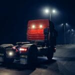 Ciężarówka jedzie nocą słabo oświetloną ulicą pod latarniami