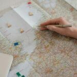 Dłoń z długopisem nad mapą Europy zaznacza planowaną trasę podróży