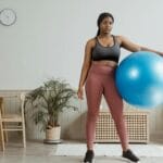 Kobieta ćwicząca z niebieską piłką fitness w salonie