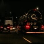 Nocny przejazd ciężarówek i aut po ciemnej trasie szybkiego ruchu