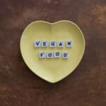 Żółty talerz w kształcie serca z napisem vegan food z klocków Scrabble