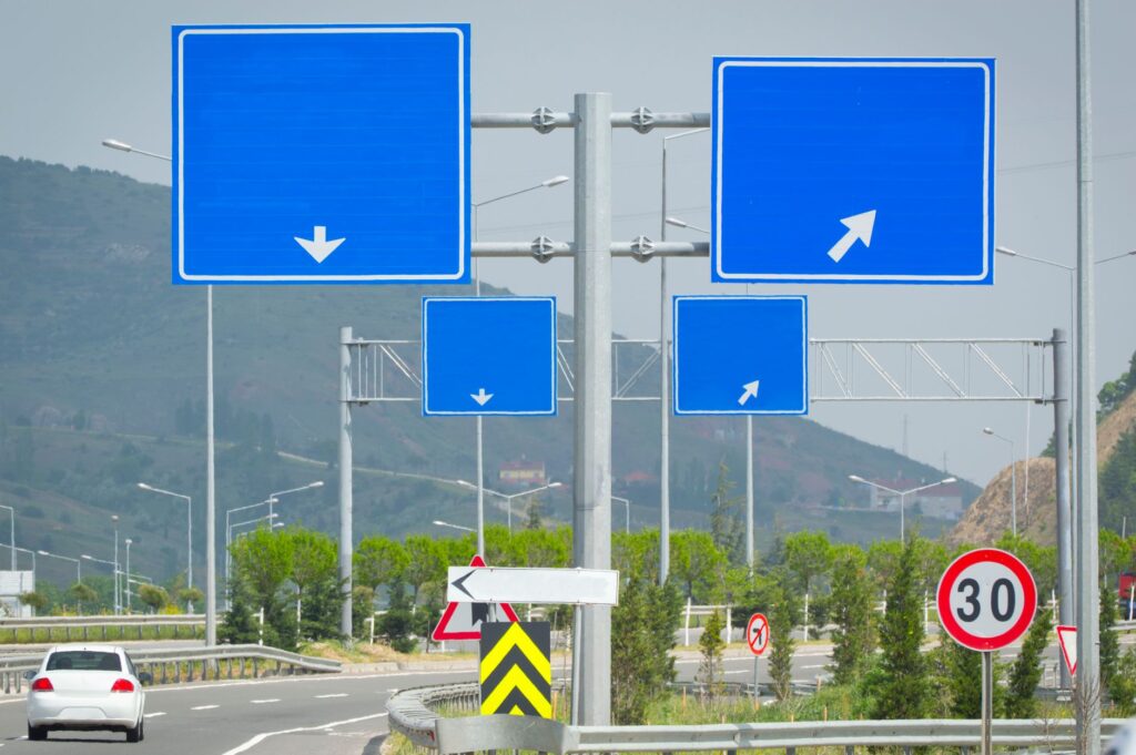 Niebieskie znaki drogowe i ograniczenie prędkości przy skrzyżowaniu autostrad